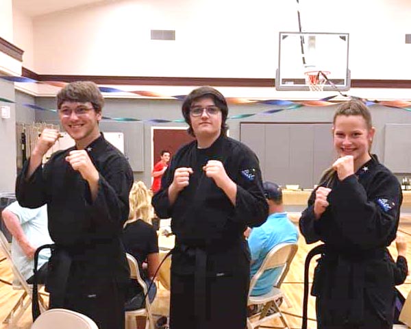 Three martial arts students earn their black belts